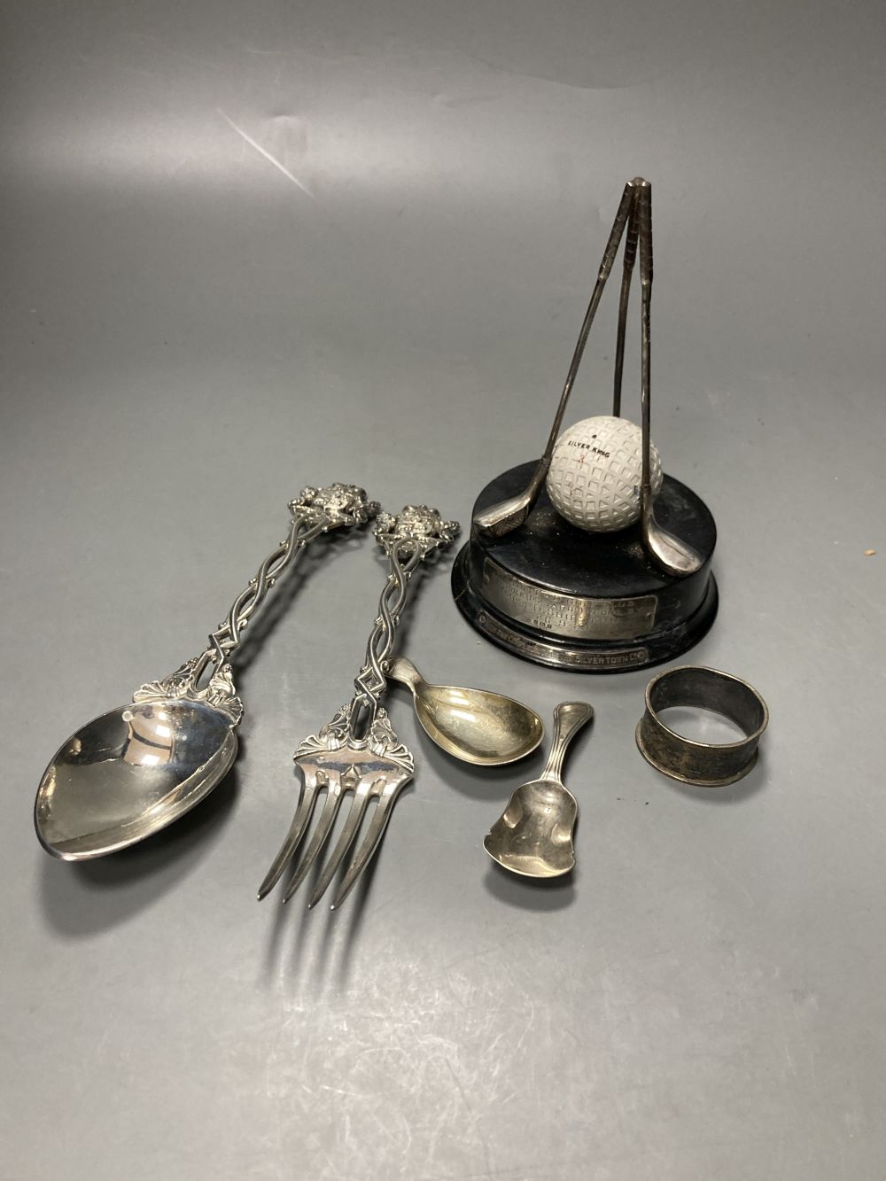 Two 19th century caddy spoons, silver napkin ring, a pair of Continental white metal servers and a golf trophy